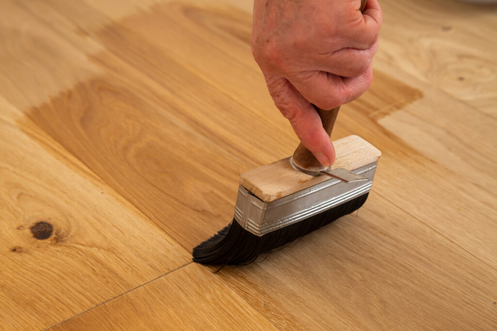 Application of oil-based floor finish on luxury oak parquet flooring, which tends to enhance the appearance of parquet